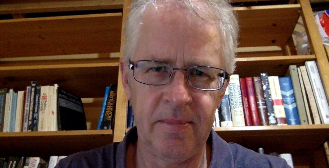 Headshot of David Kimbell against background of books on a bookshelf